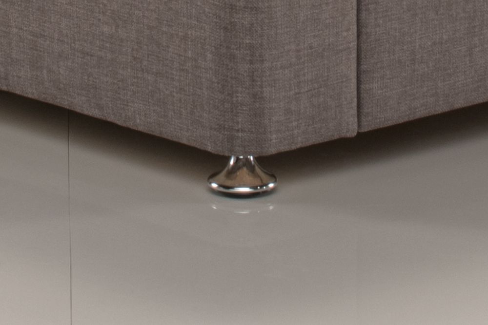 A couch with chrome legs is sitting on a tiled floor.