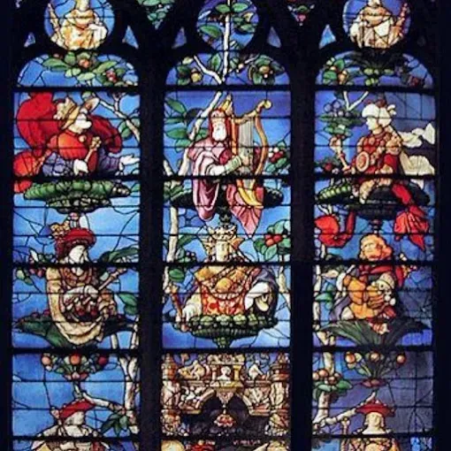 Persona ensamblando vidrieras de colores en un banco de trabajo de madera en un taller.