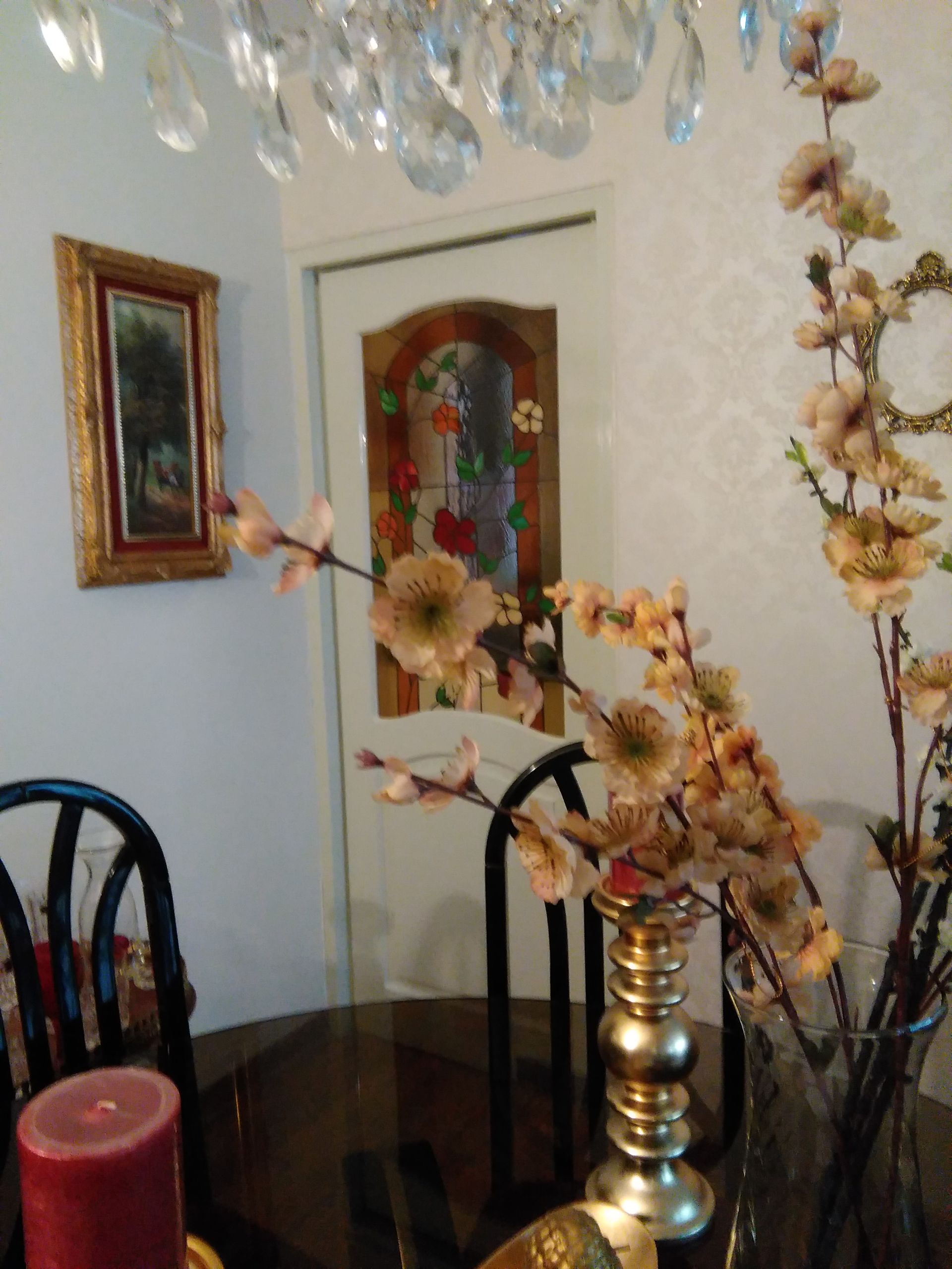 Panel floral de vidrieras con flores rojas, amarillas y azules en un marco de madera sobre una mesa en un estudio.