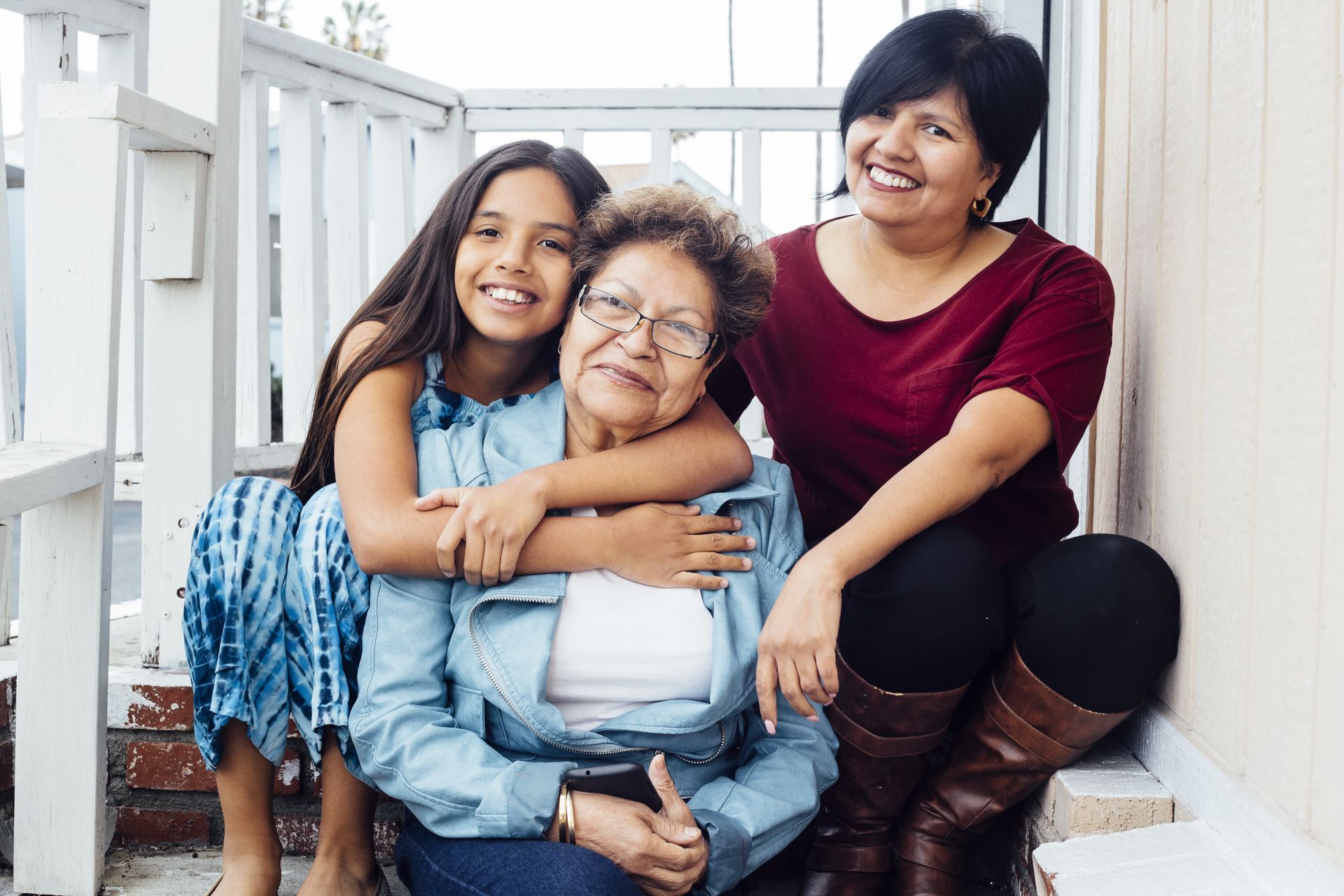 Woman with dark hair and glasses smiles, wearing a yellow sweater. She sits in an office setting.