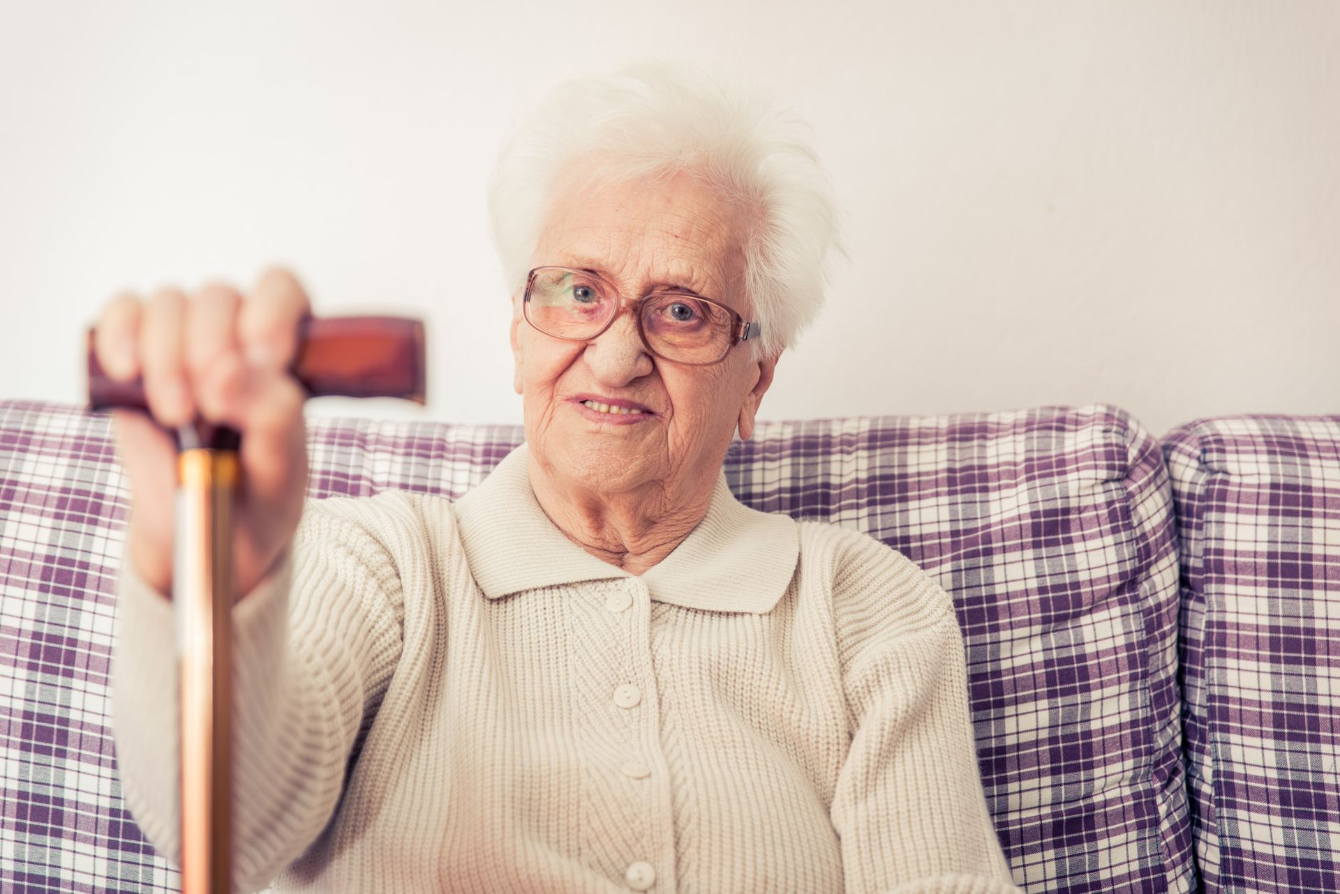 An elderly man in green sweater with a nurse in blue scrubs; indoors, smiling.