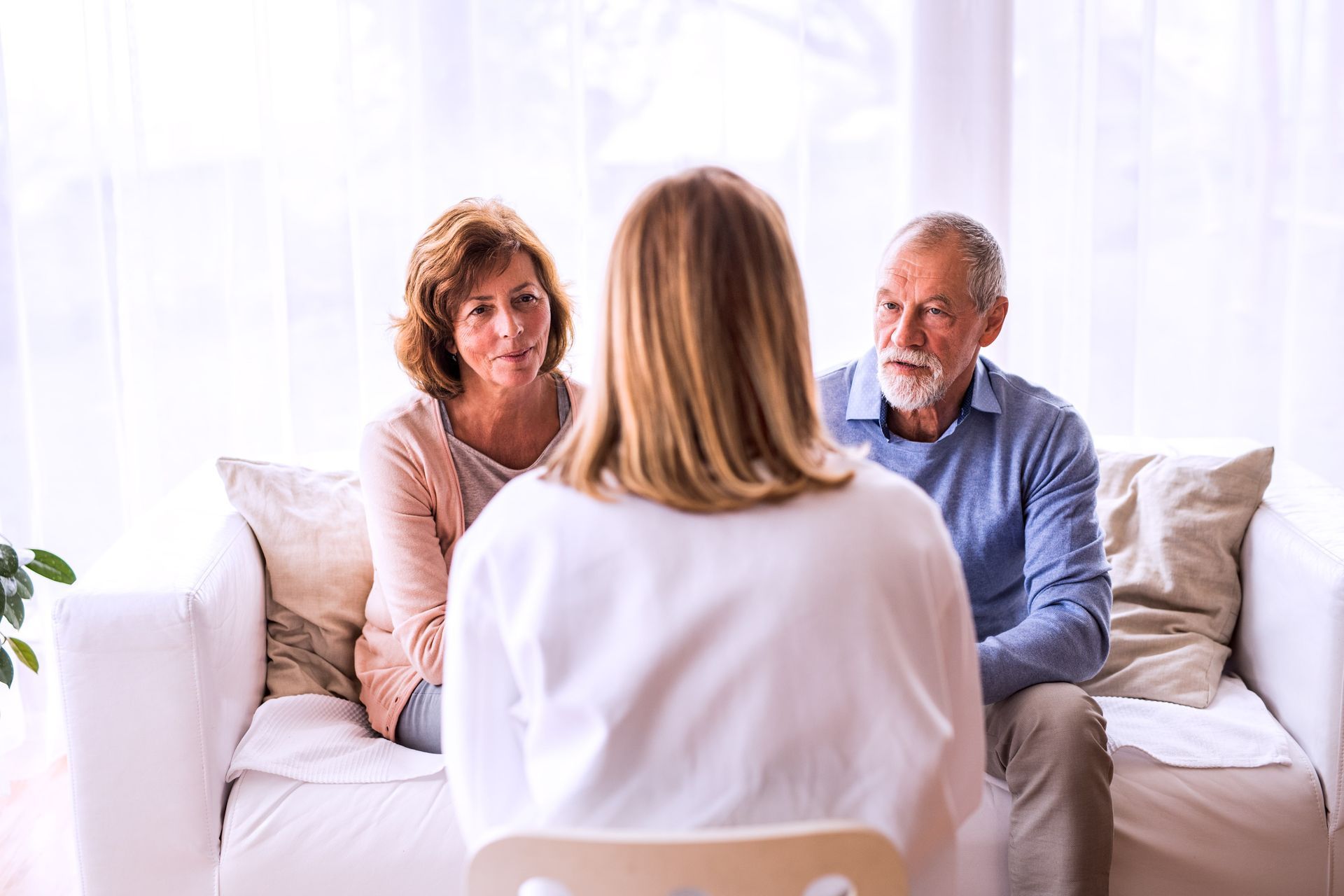 Woman talking to therapist on a sofa in a counseling session; indoor setting.