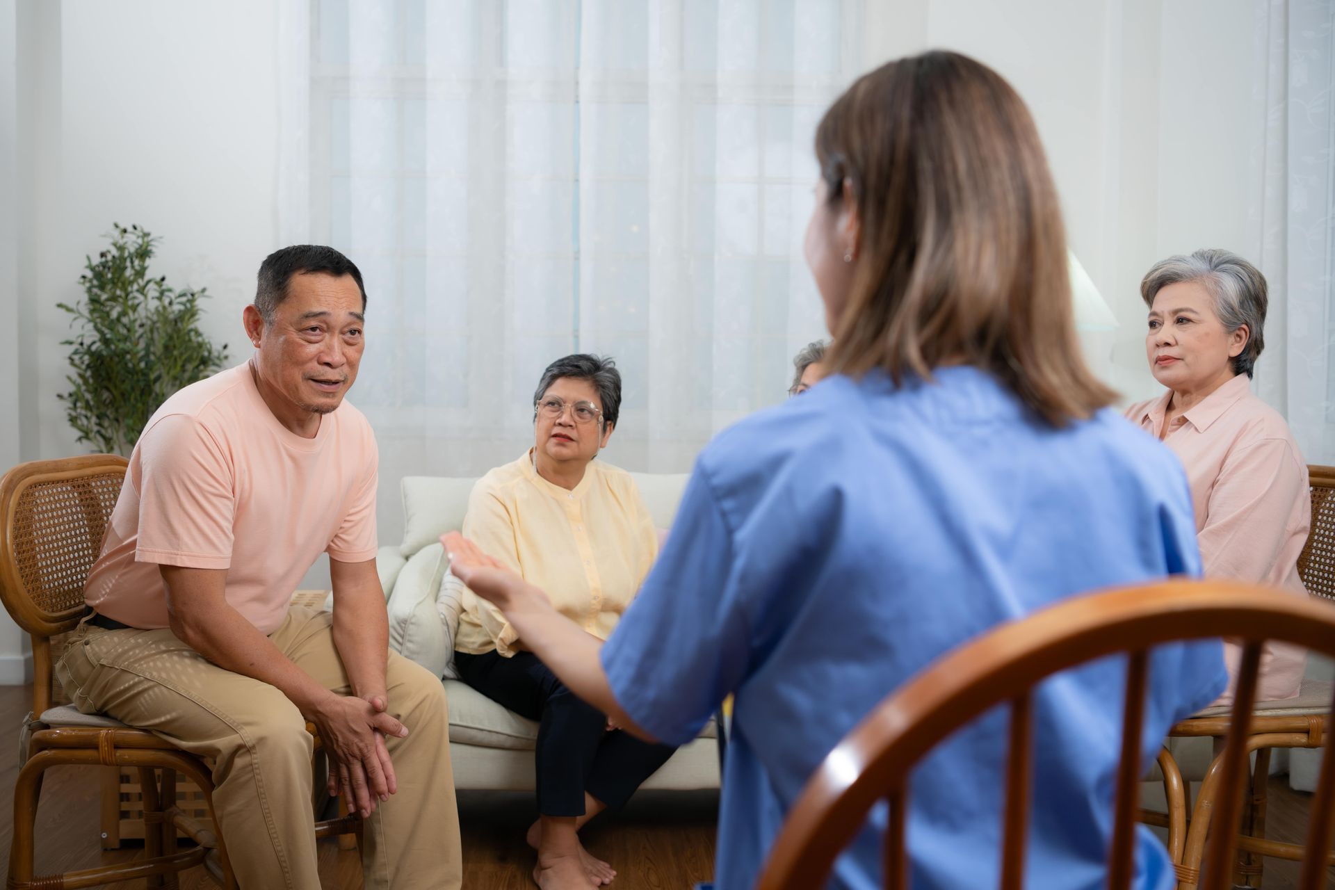 Therapist in green dress taking notes as patient gestures with hands; counseling session.