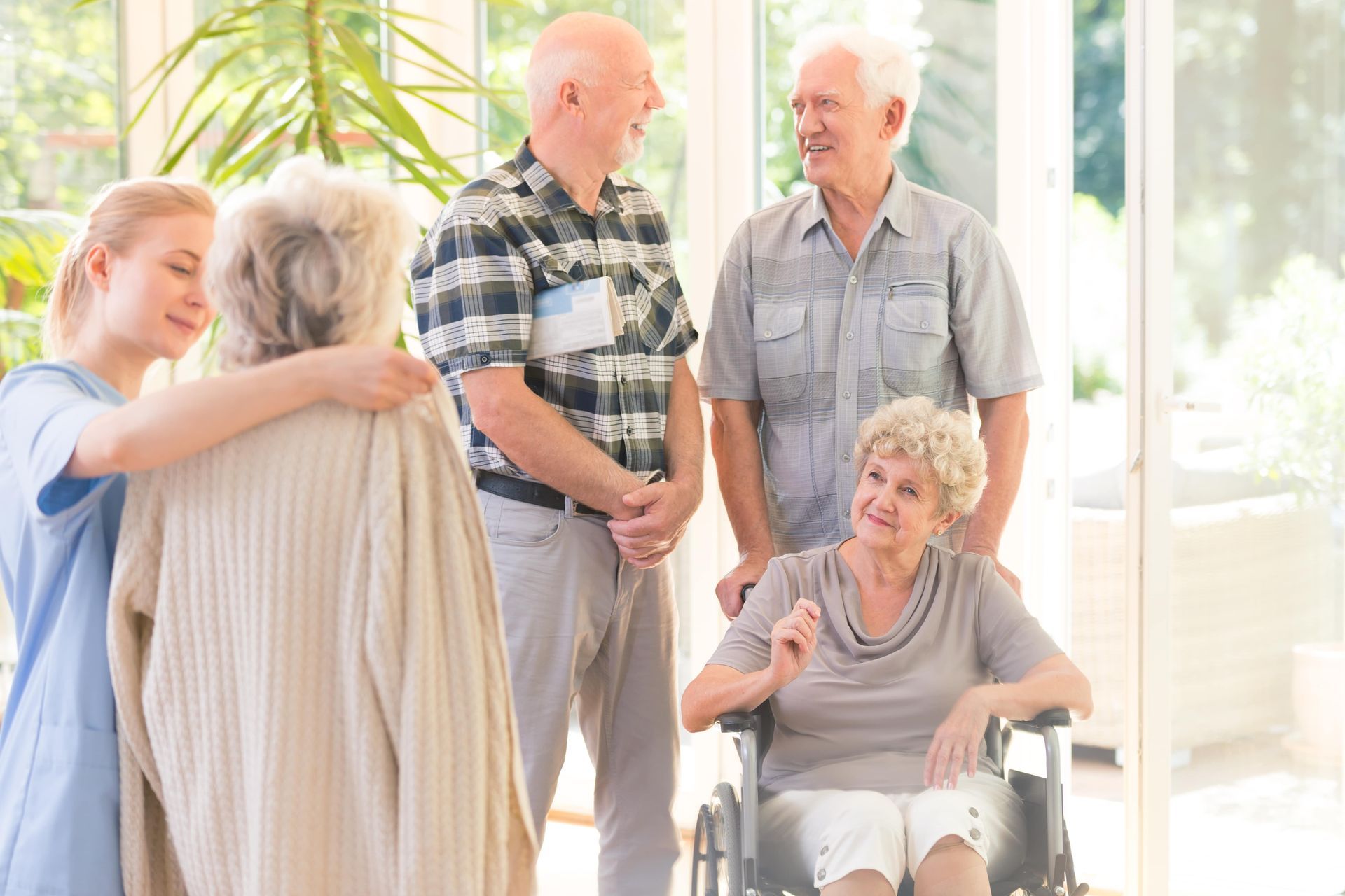 Woman holding a triangle, smiling at an elderly woman in a home.