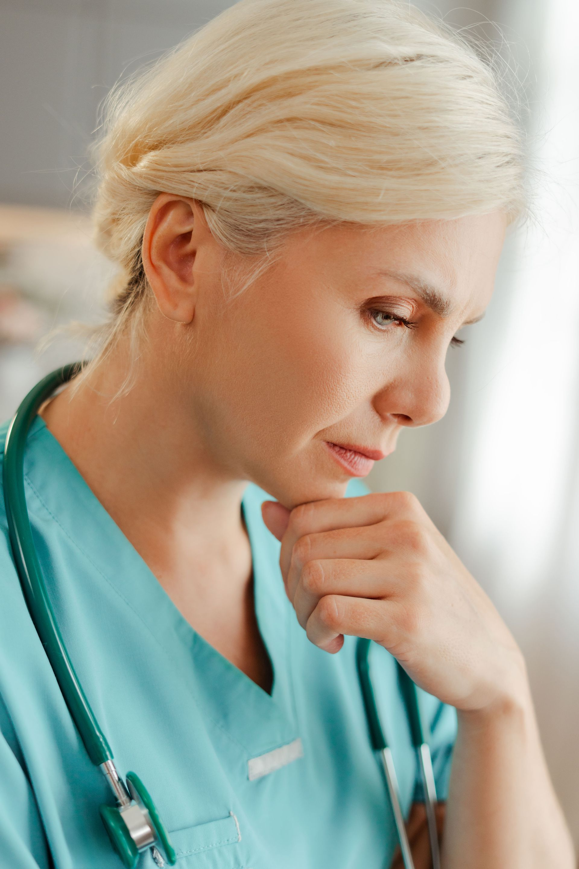 Caregiver smiles at elderly woman in wheelchair outdoors, red roses in foreground.