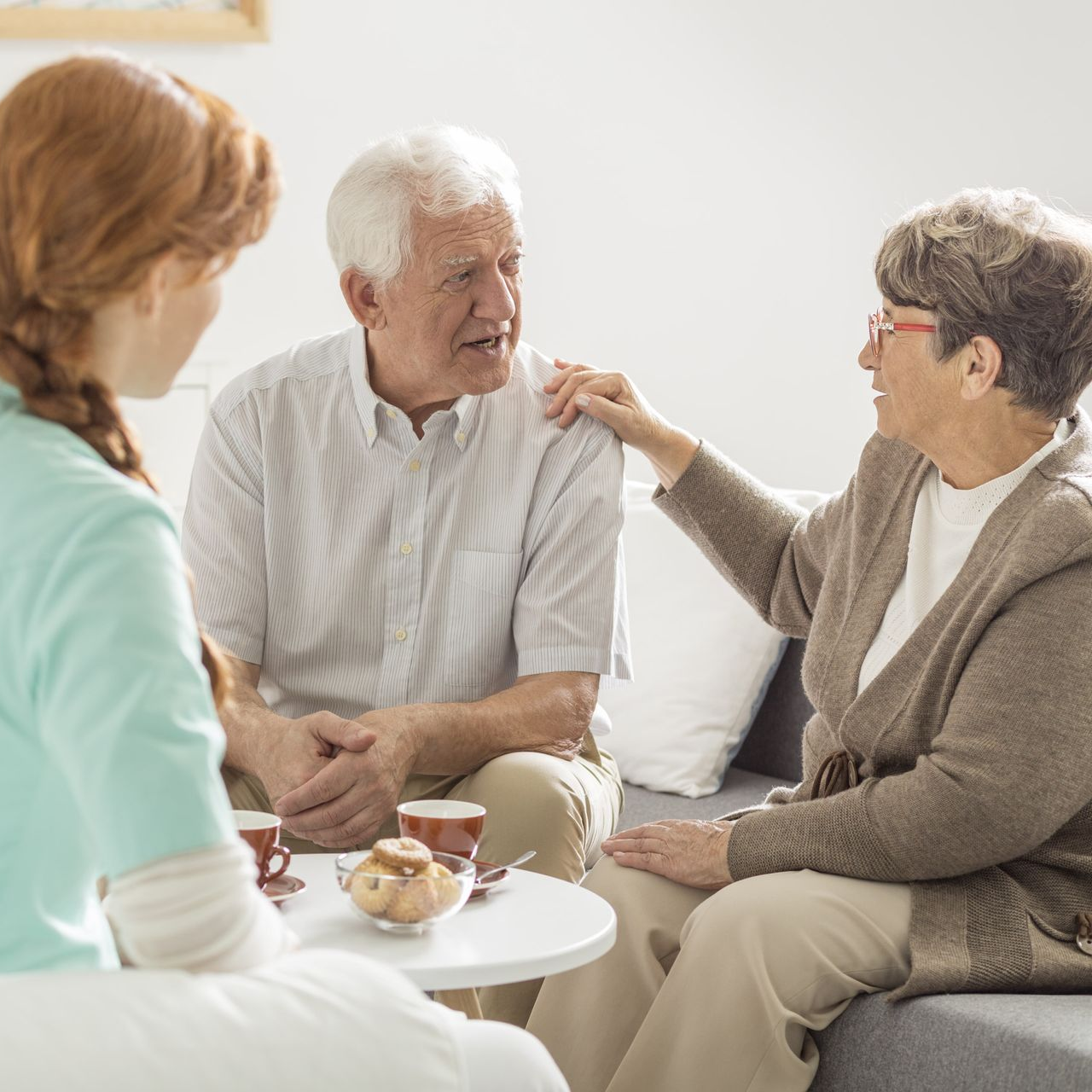 Woman in therapy session, sitting on beanbags, smiling, talking to a therapist by a window.
