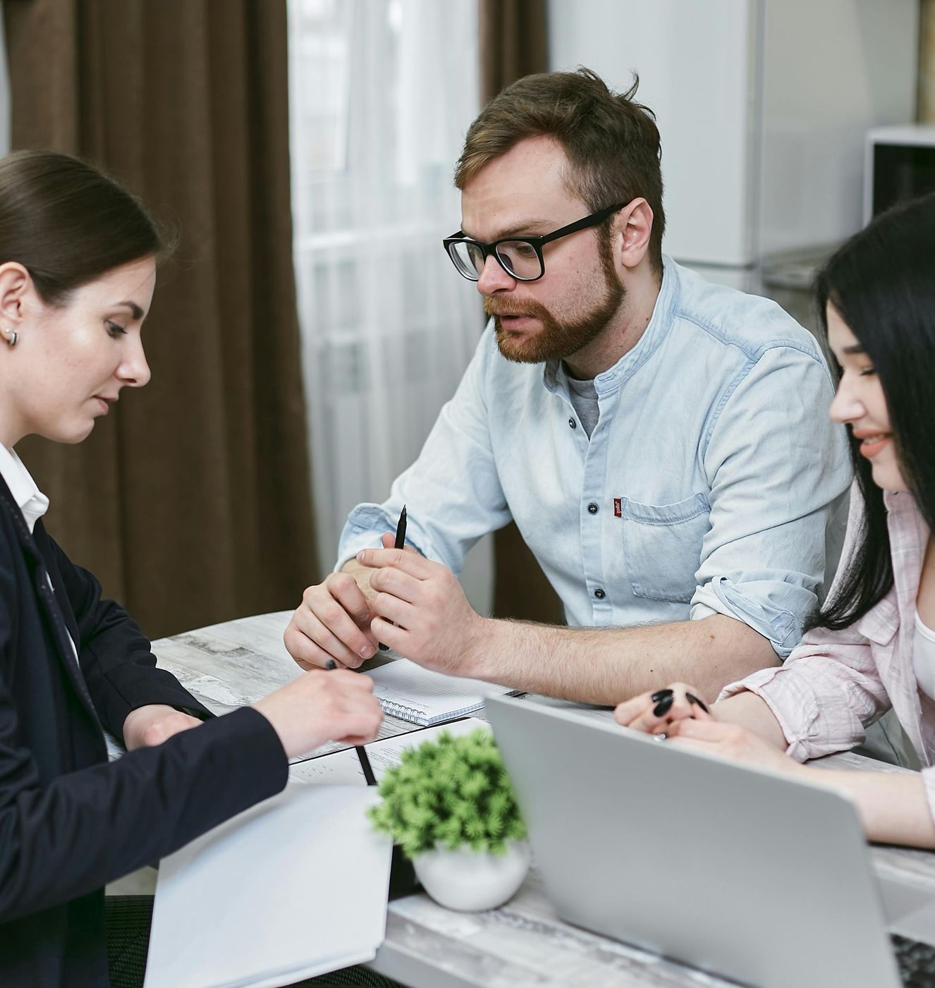 A group of people are sitting at a table with laptops.