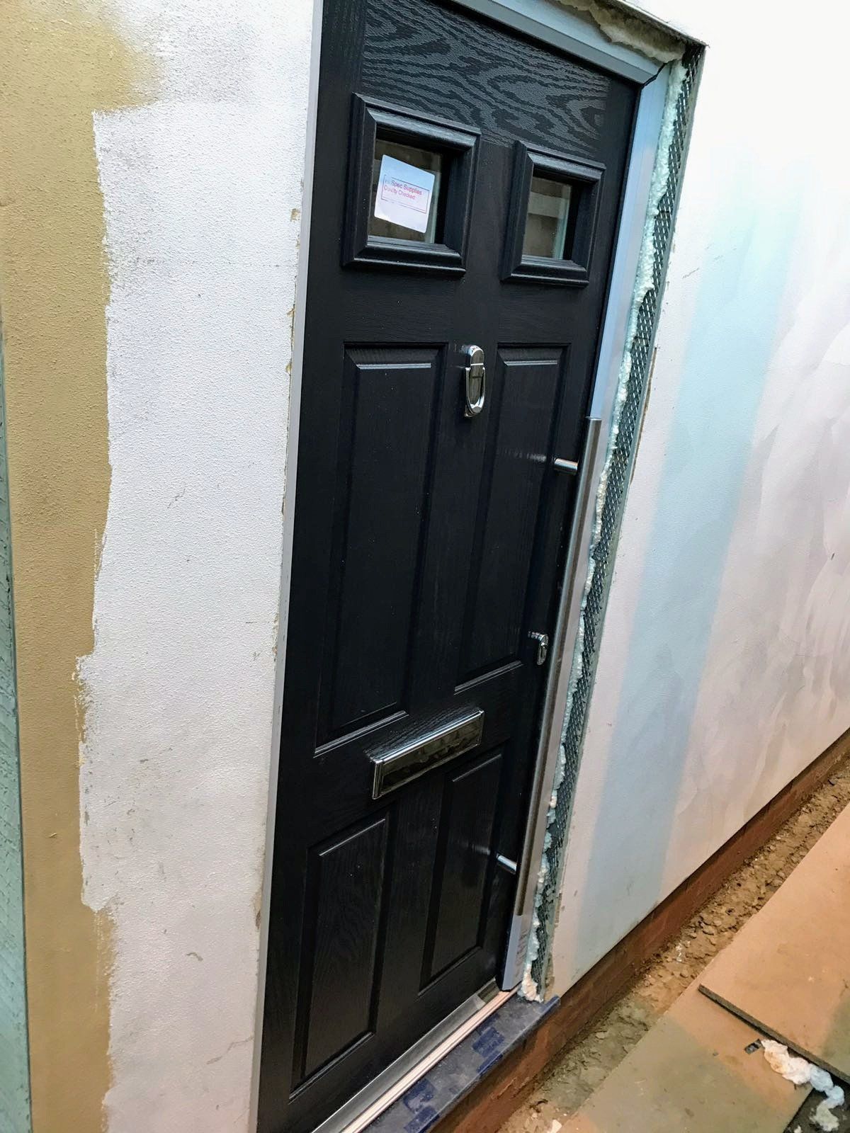 A black door is sitting on a white wall.