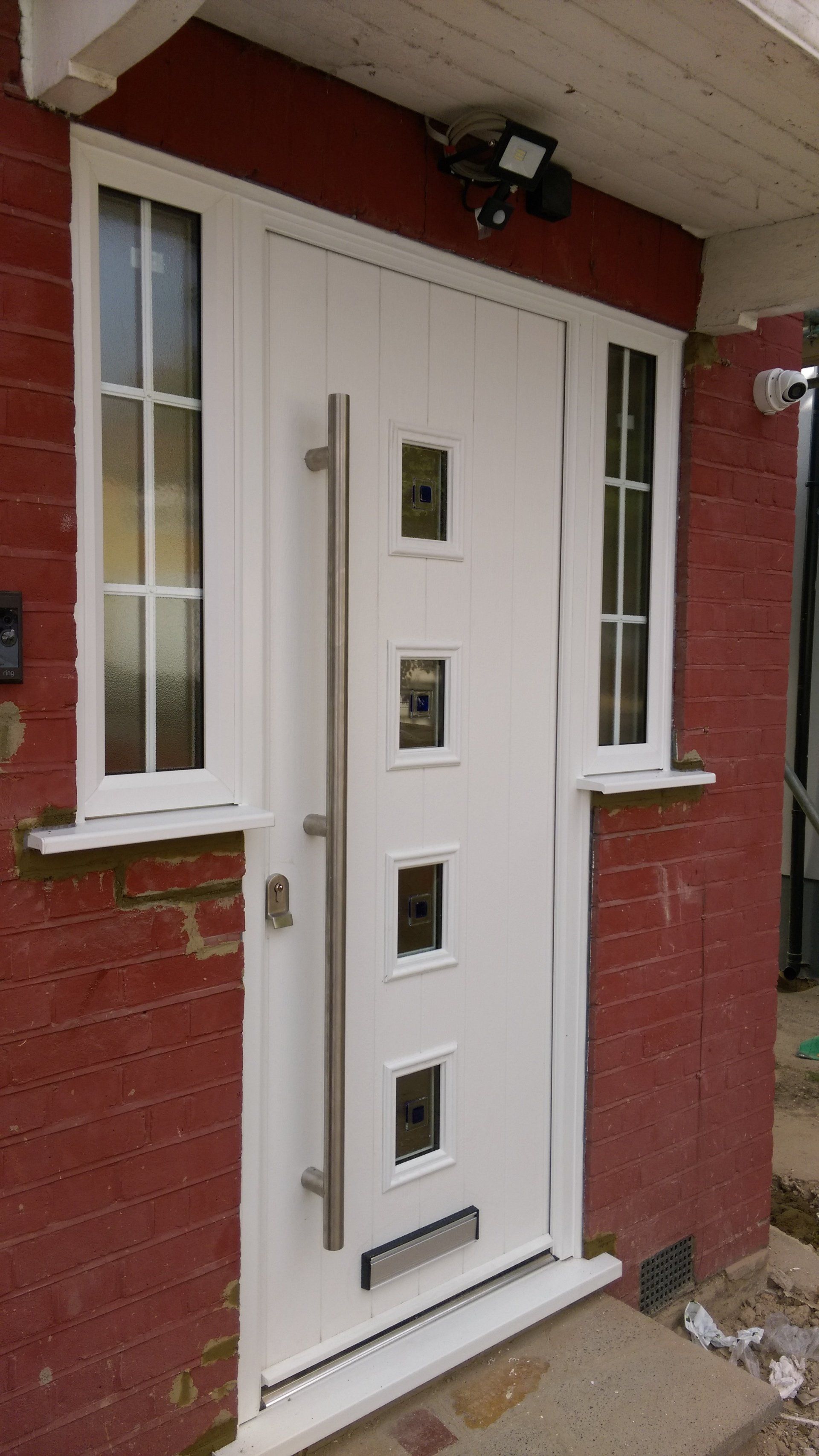 A white door with a stainless steel handle is on a red brick building.