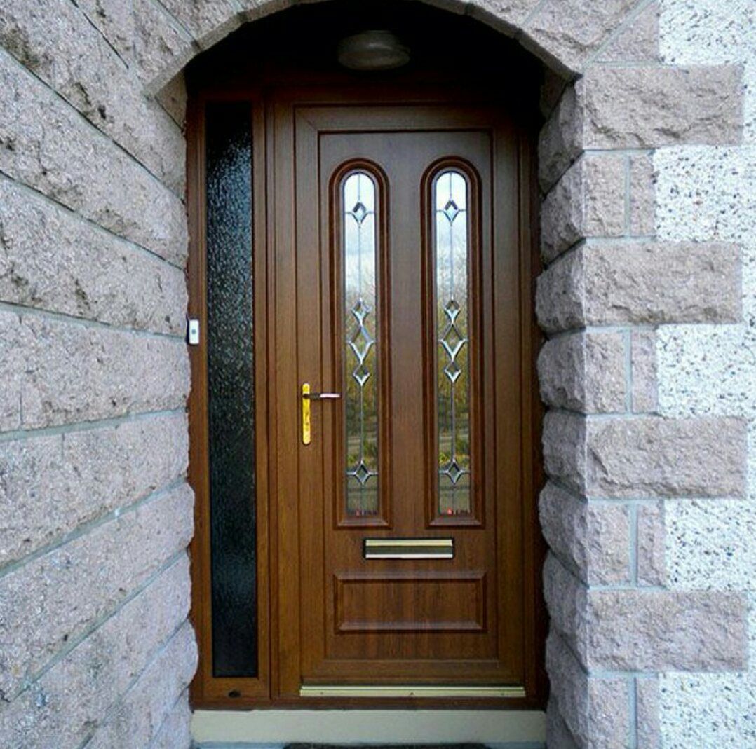 A wooden door with stained glass is surrounded by bricks