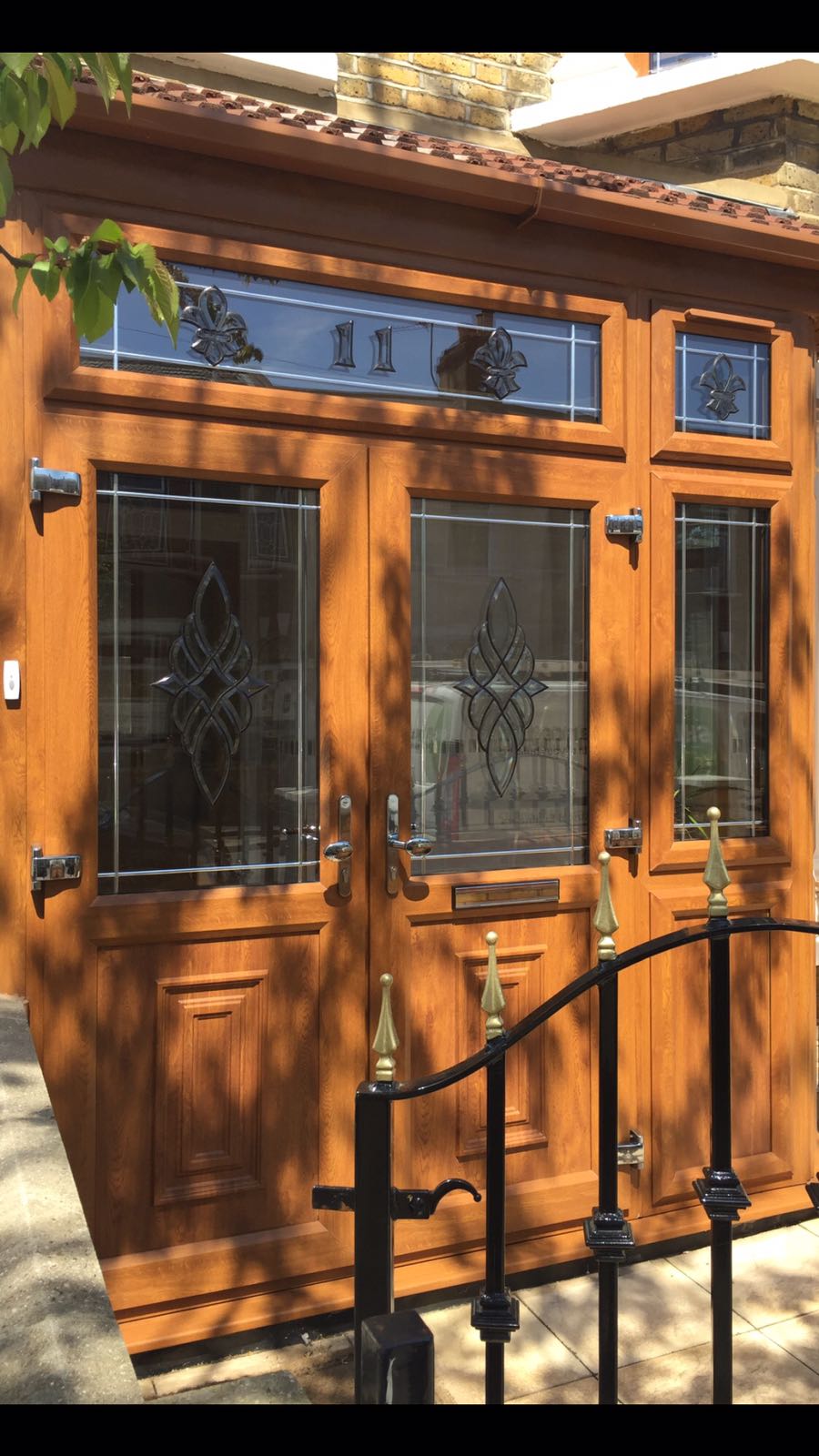 A wooden door with stained glass windows is sitting next to a black fence.