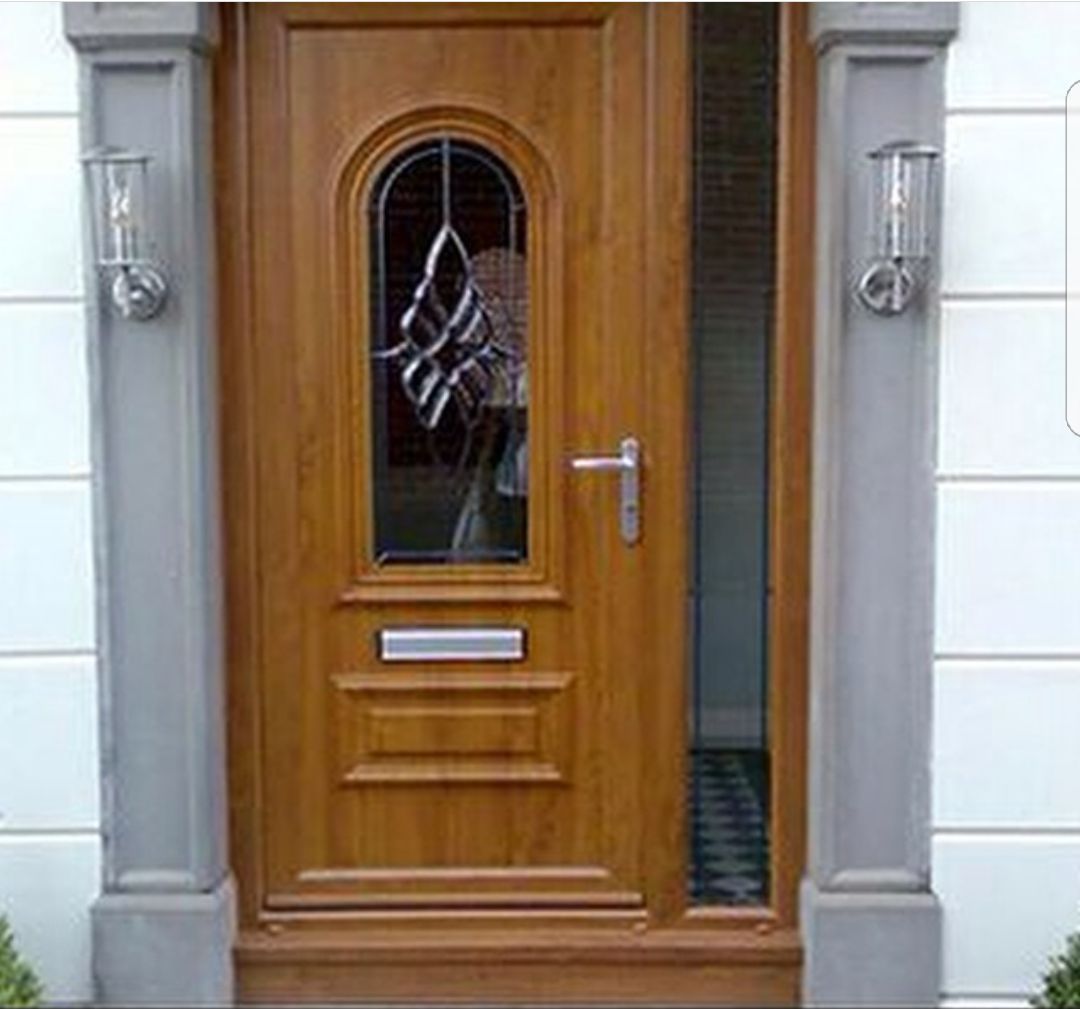 A wooden door with a stained glass window is on the side of a building.