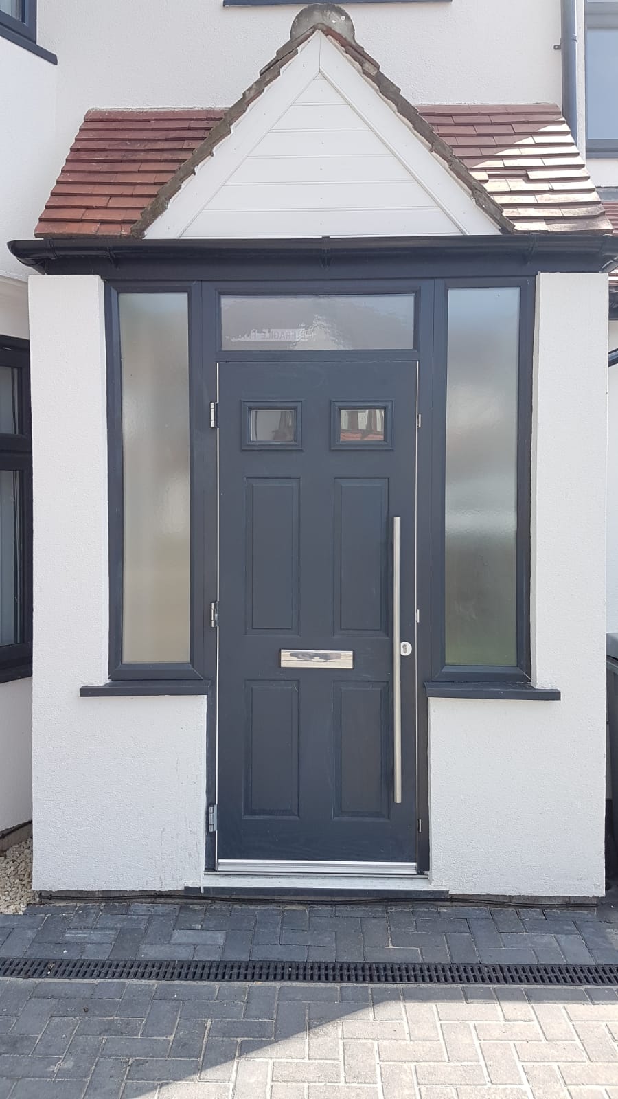 The front door of a house with a porch and a black door.