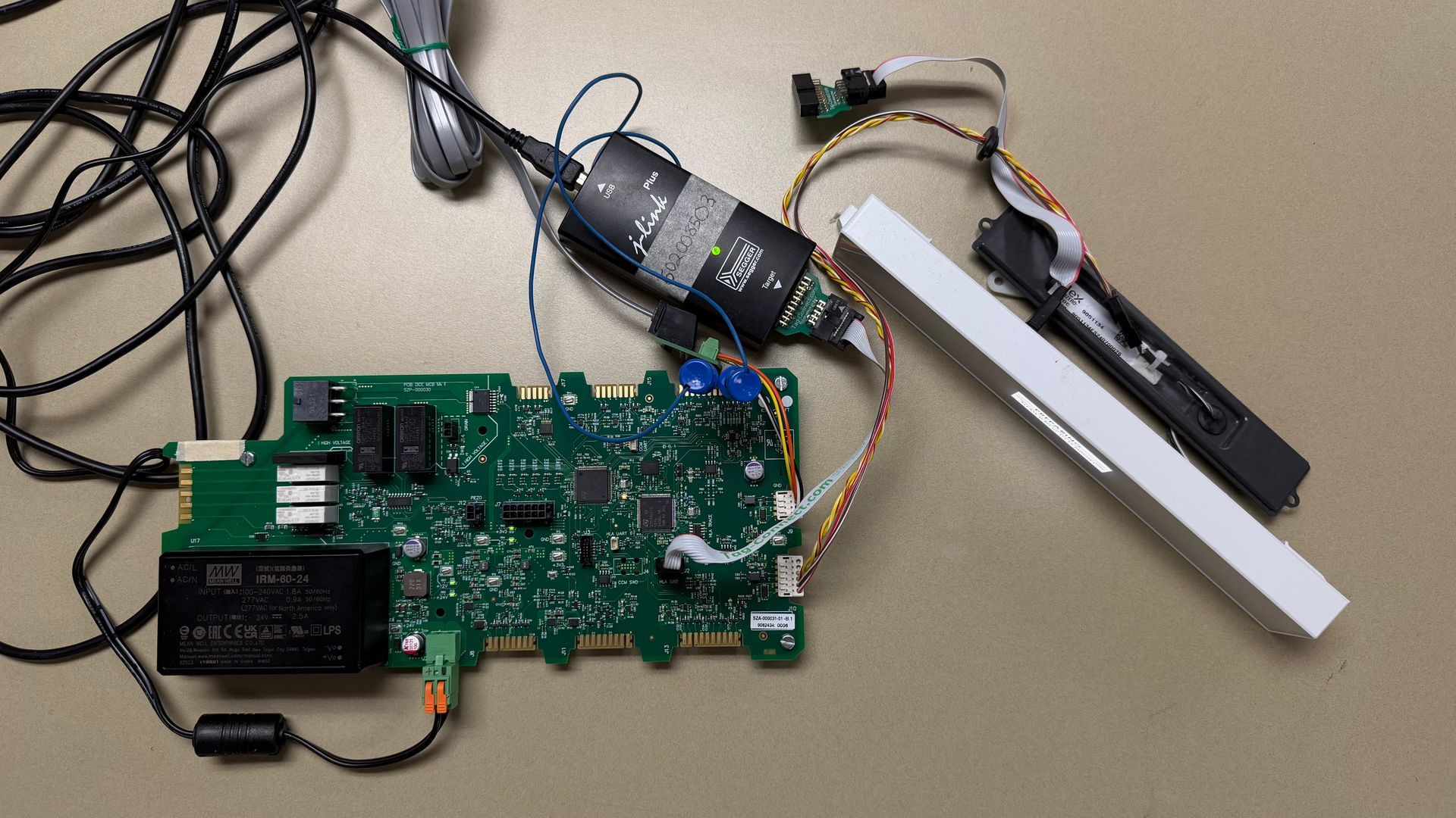 A green circuit board connected by ribbon cables to a black camera module and a rectangular white infrared light bar.