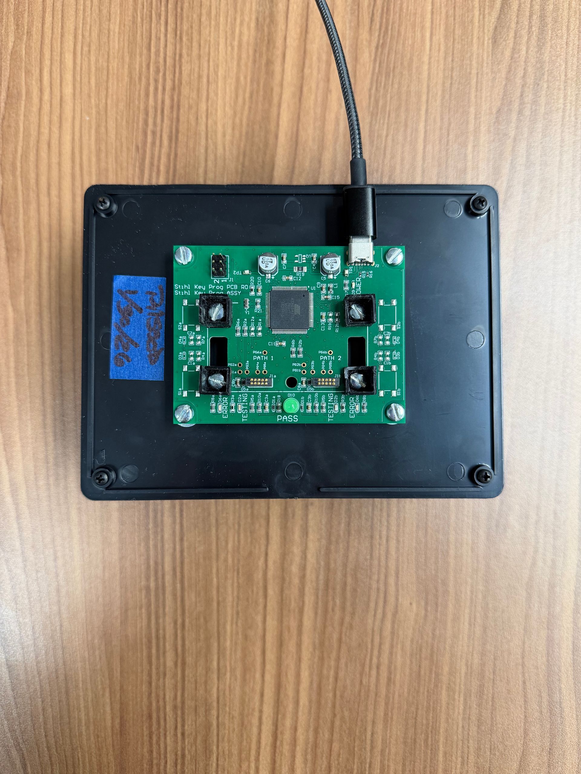 A green circuit board with four sensors and a central microchip, mounted on a black plastic case with a power cable.