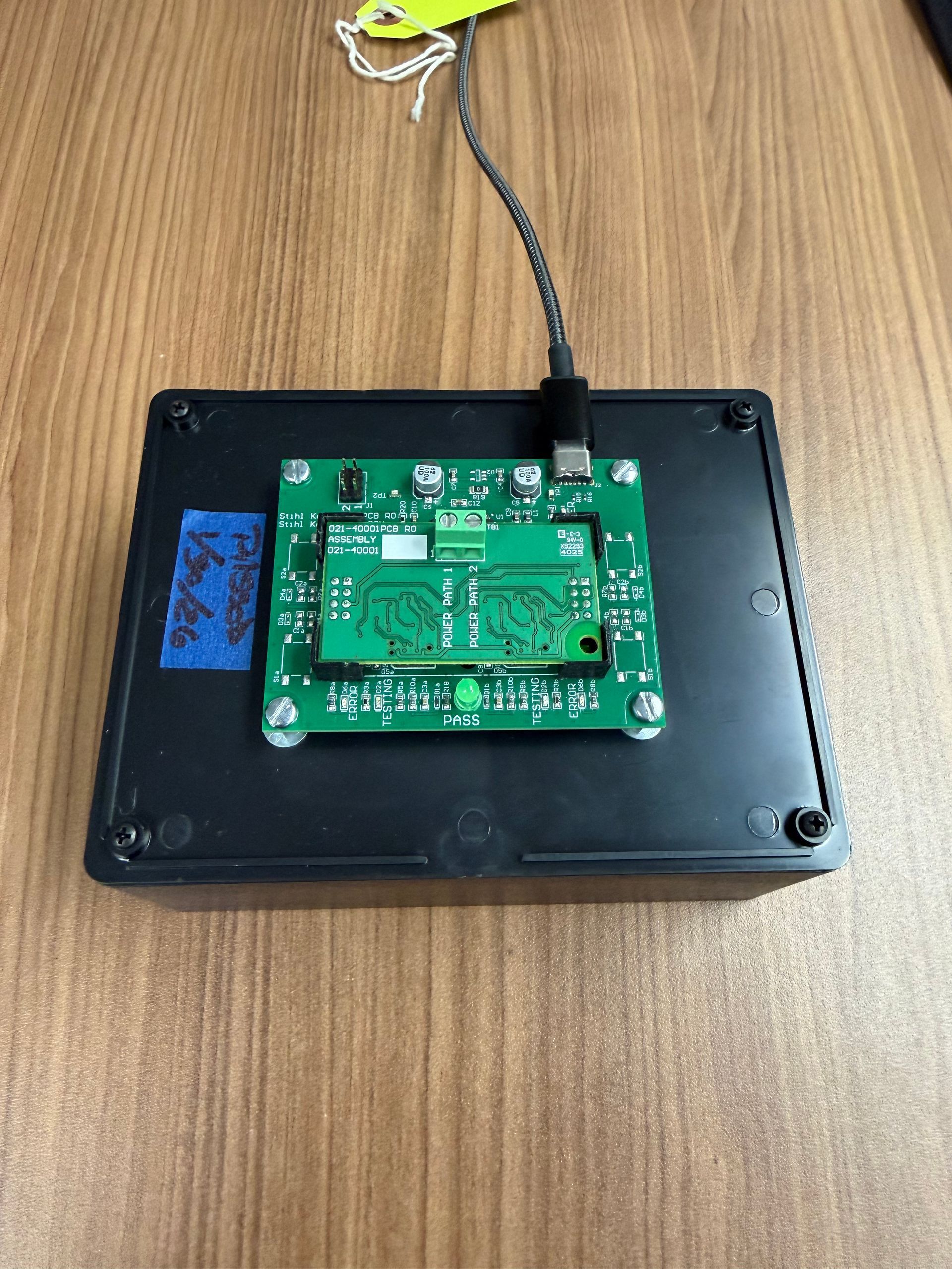 A green circuit board is mounted on top of a black plastic box, with a cable plugged into the board's USB-C port.