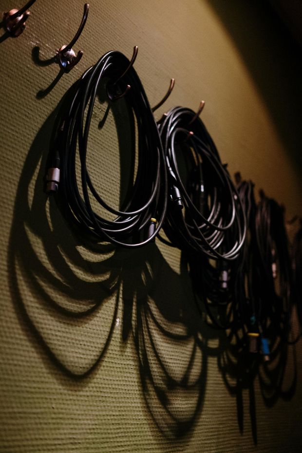 A bunch of wires are hanging on hooks on a wall