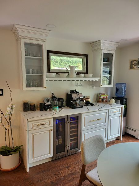 White built-in coffee/bar station with marble countertop, cabinets, and small window above.