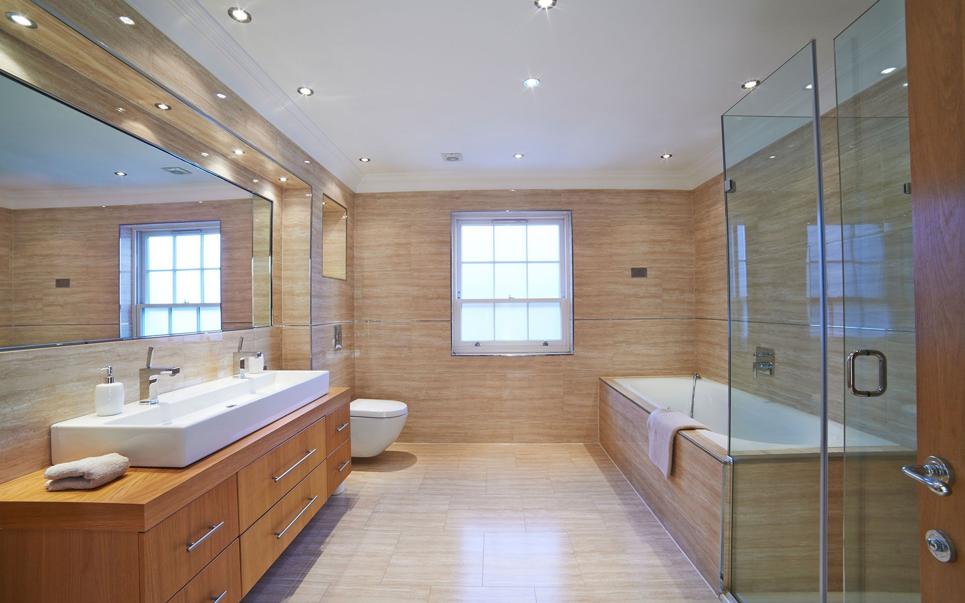 Modern bathroom with a large mirror, a rectangular sink, a bathtub, and a glass shower door.