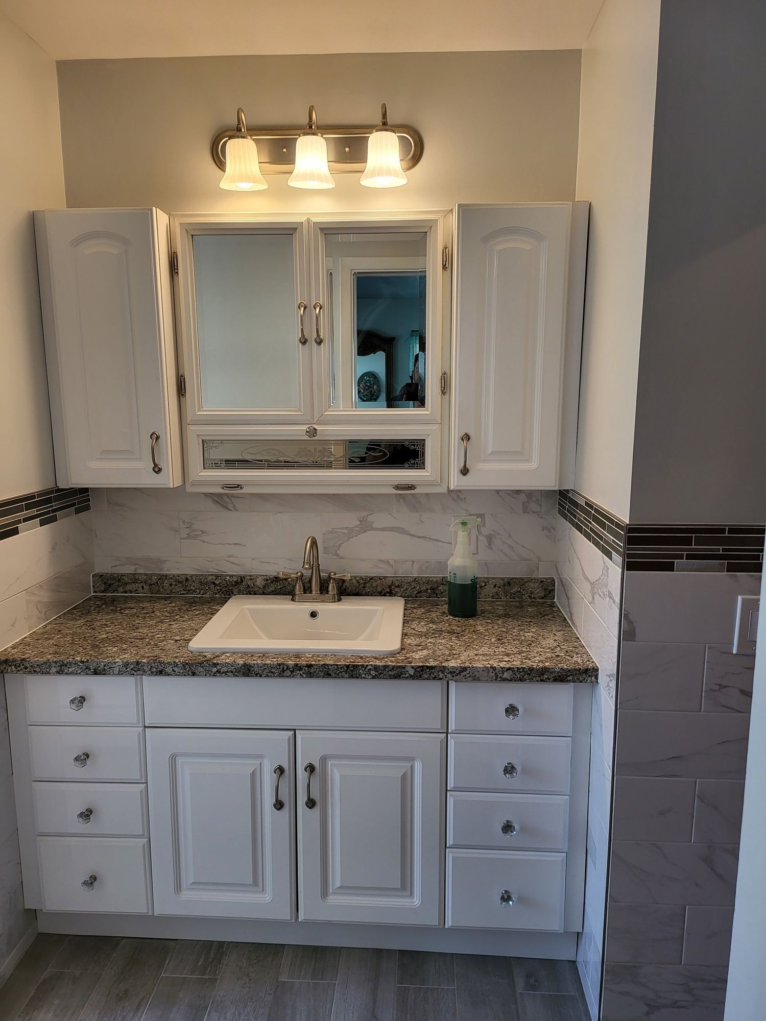 White bathroom vanity with overhead cabinets, sink, and countertop.