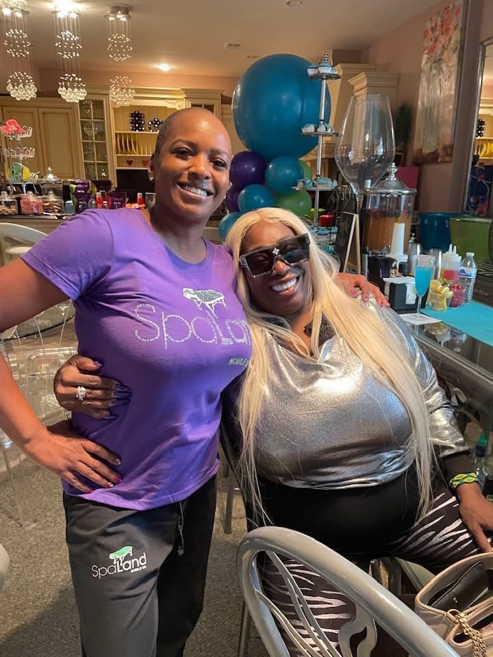 Two women are posing for a picture in a room with balloons.
