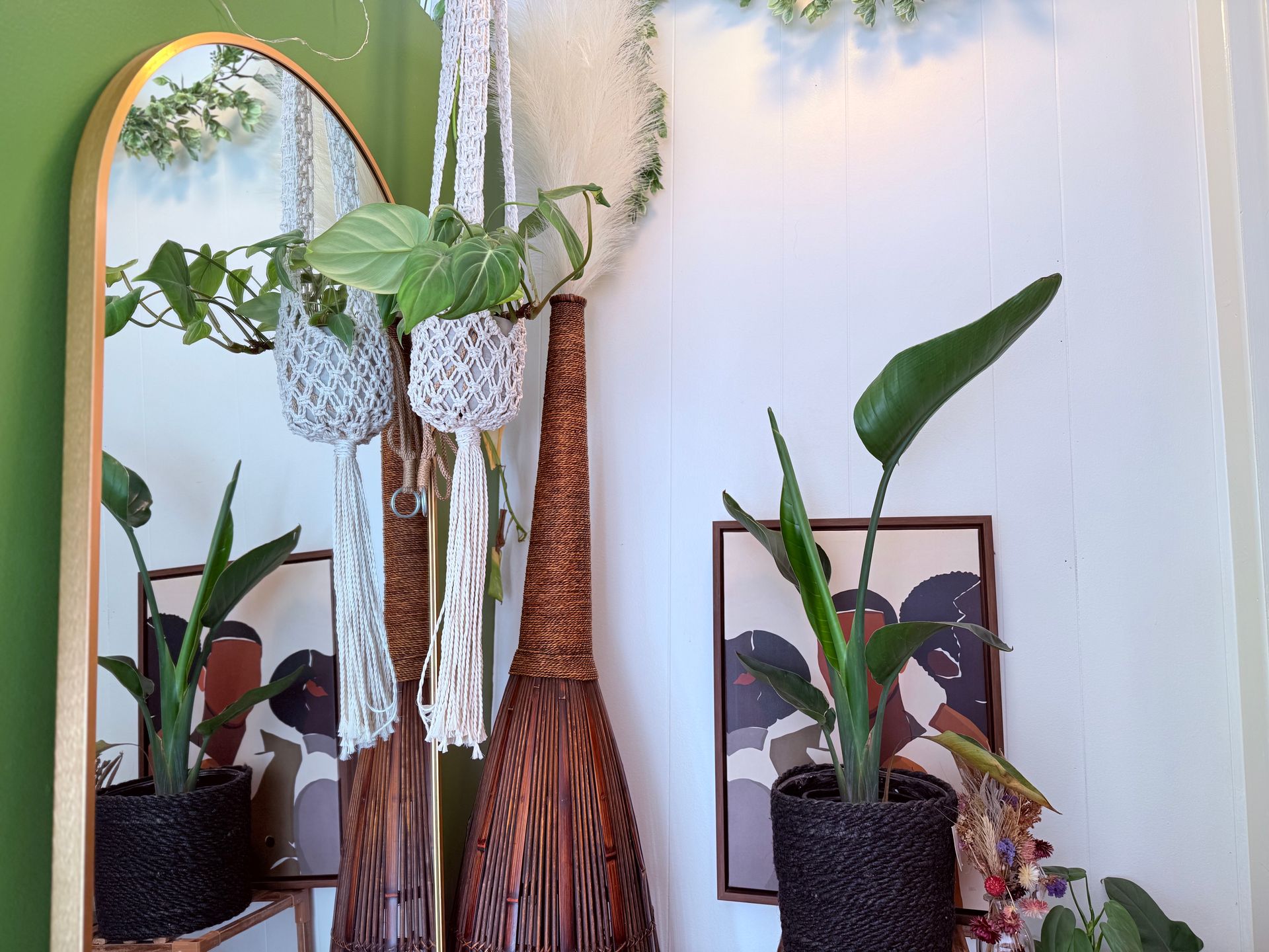 A room with a mirror , vases and potted plants.