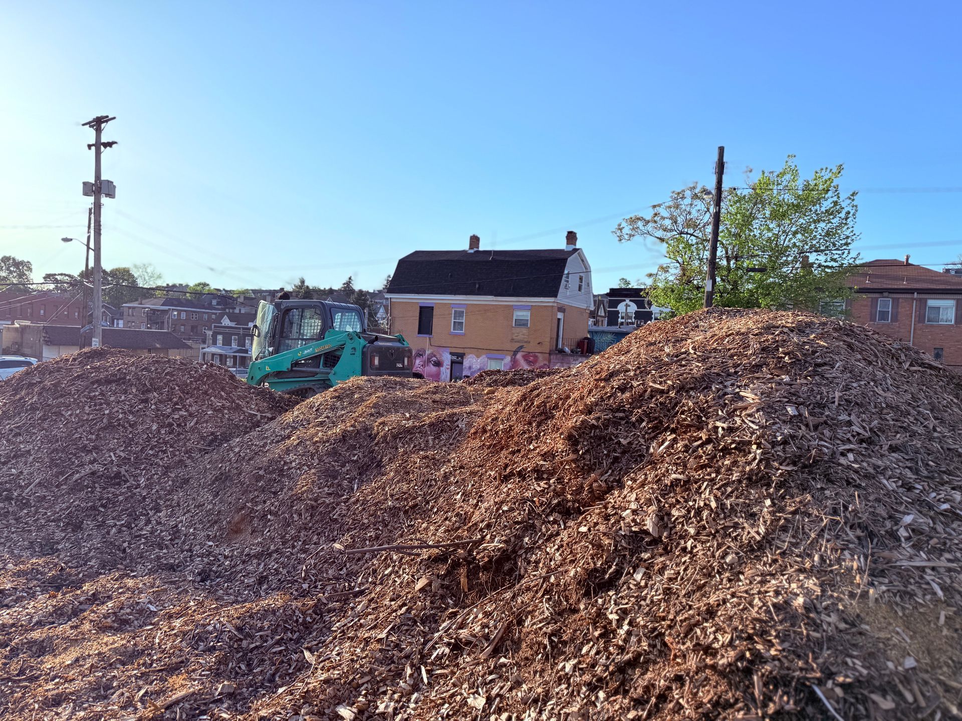 A large pile of wood chips is sitting in front of a house.