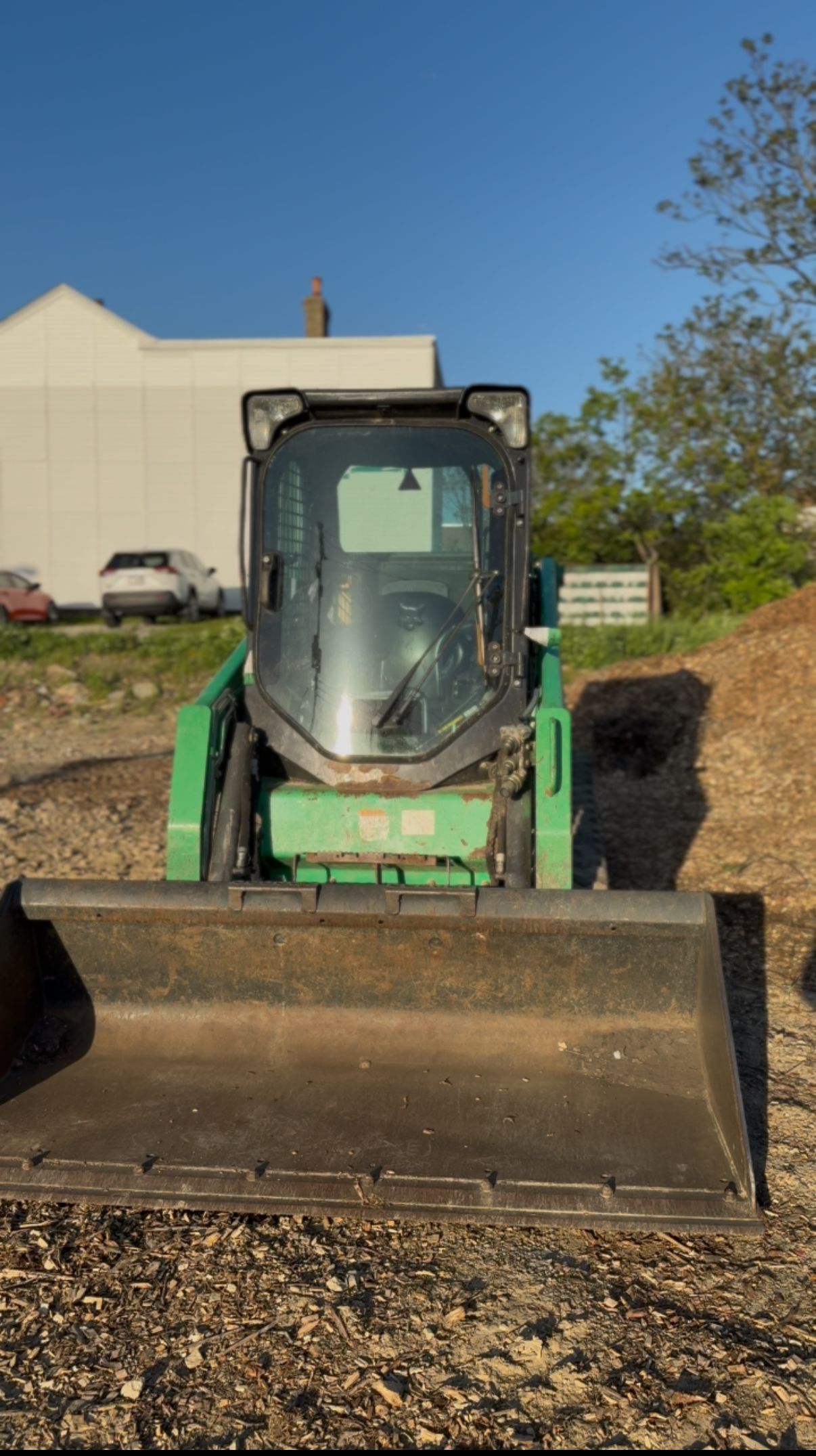 A green bulldozer is sitting on top of a dirt field.
