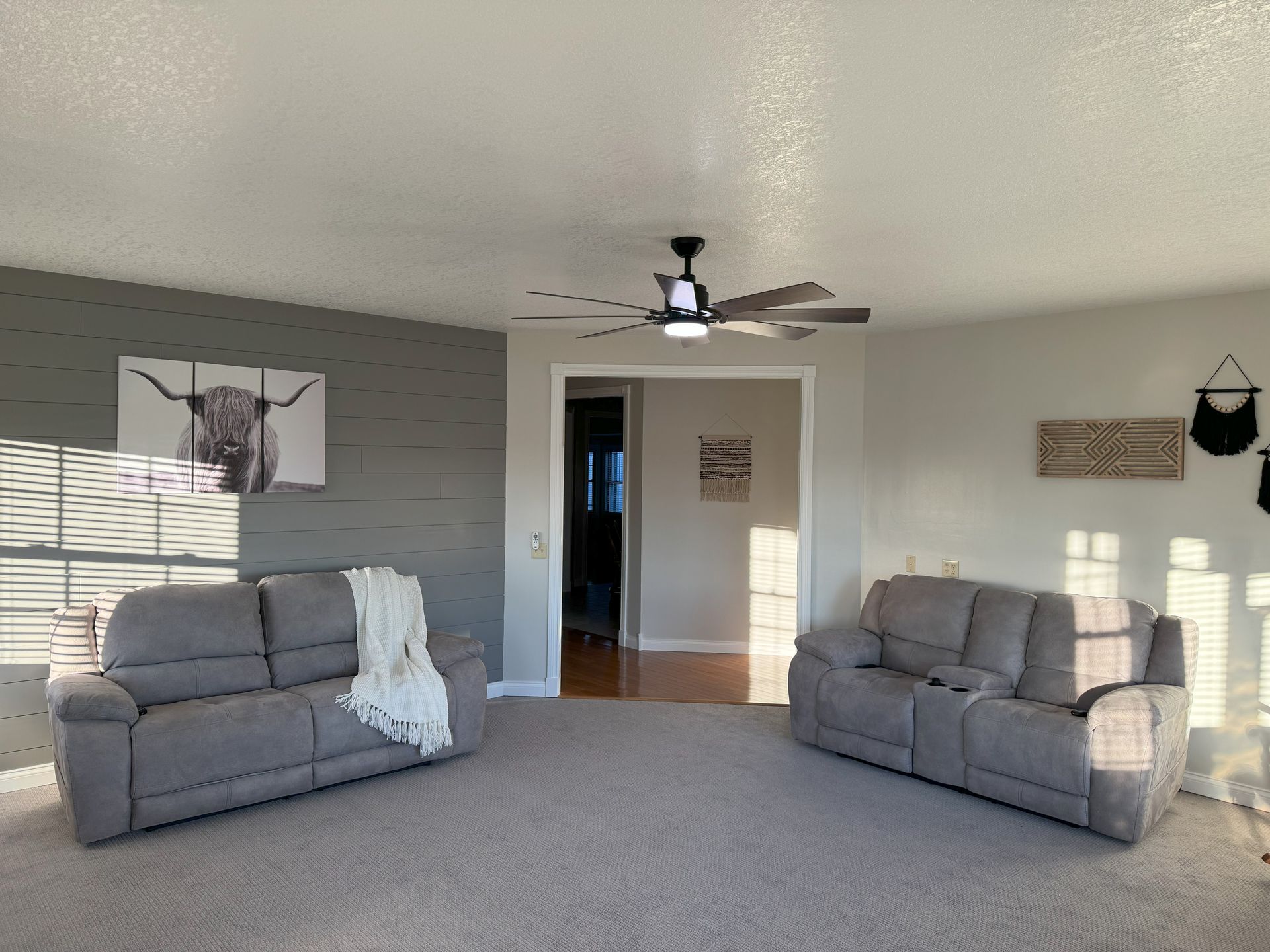 A living room with two couches and a ceiling fan.