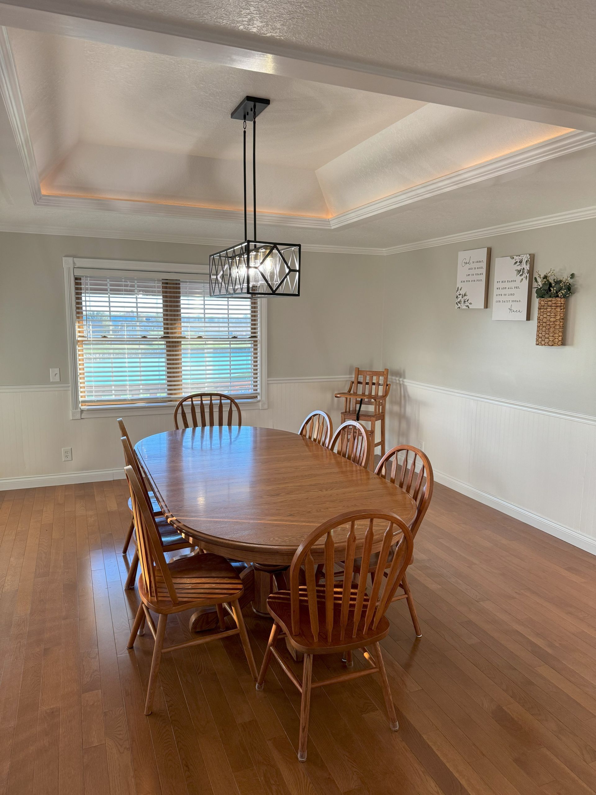 A dining room with a table and chairs and a chandelier hanging from the ceiling.
