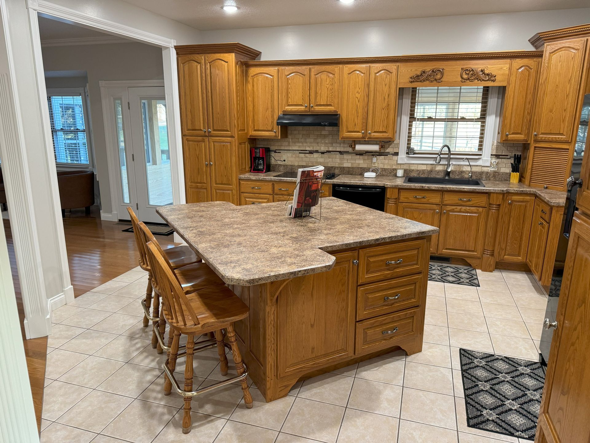 A kitchen with wooden cabinets , granite counter tops , and a large island.