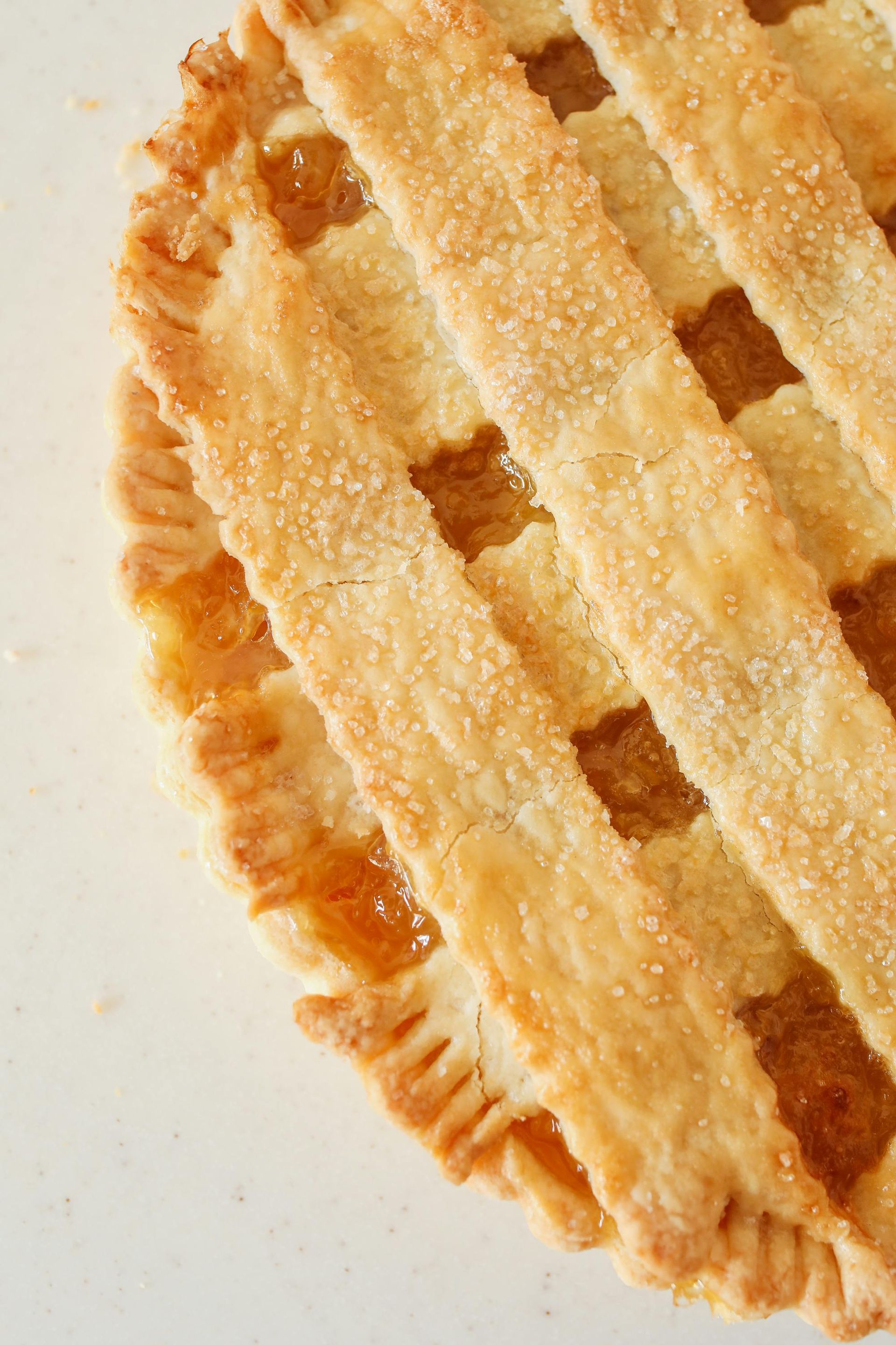 A close up of a pie with a lattice crust on a white surface.