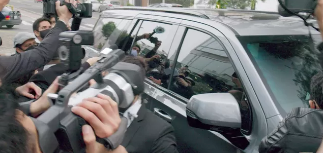 A group of people are taking pictures of a car with cameras.