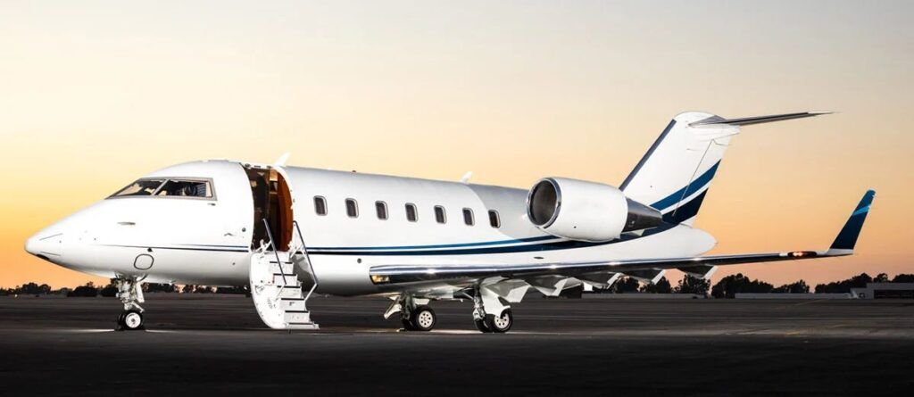 A private jet is parked on a runway at sunset.