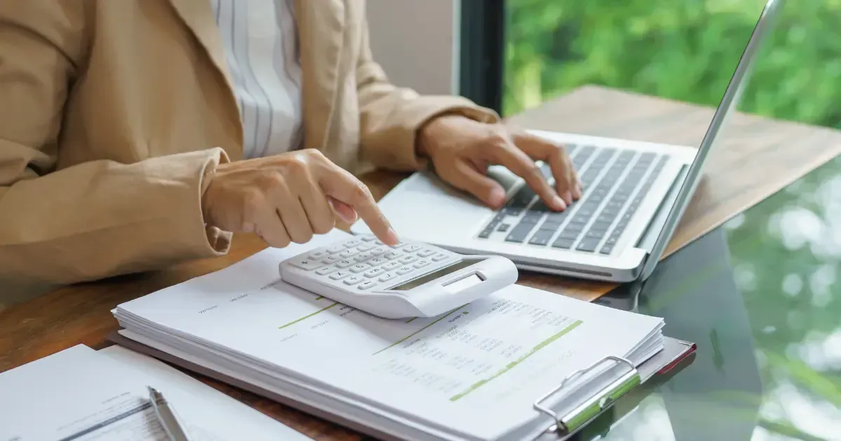 woman typing on a calculator and laptop