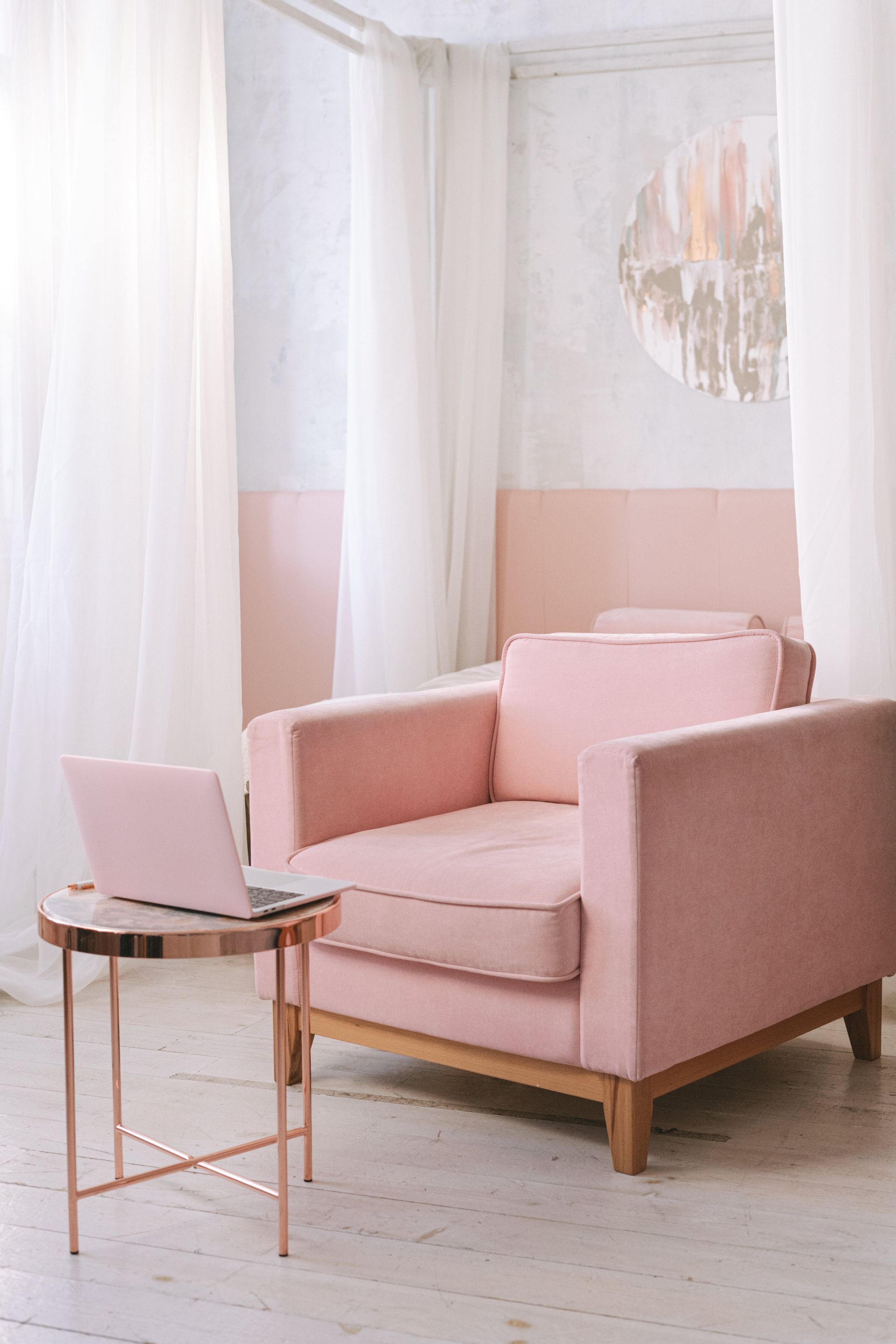 pink chair with a laptop on a table surrounded by curtains 