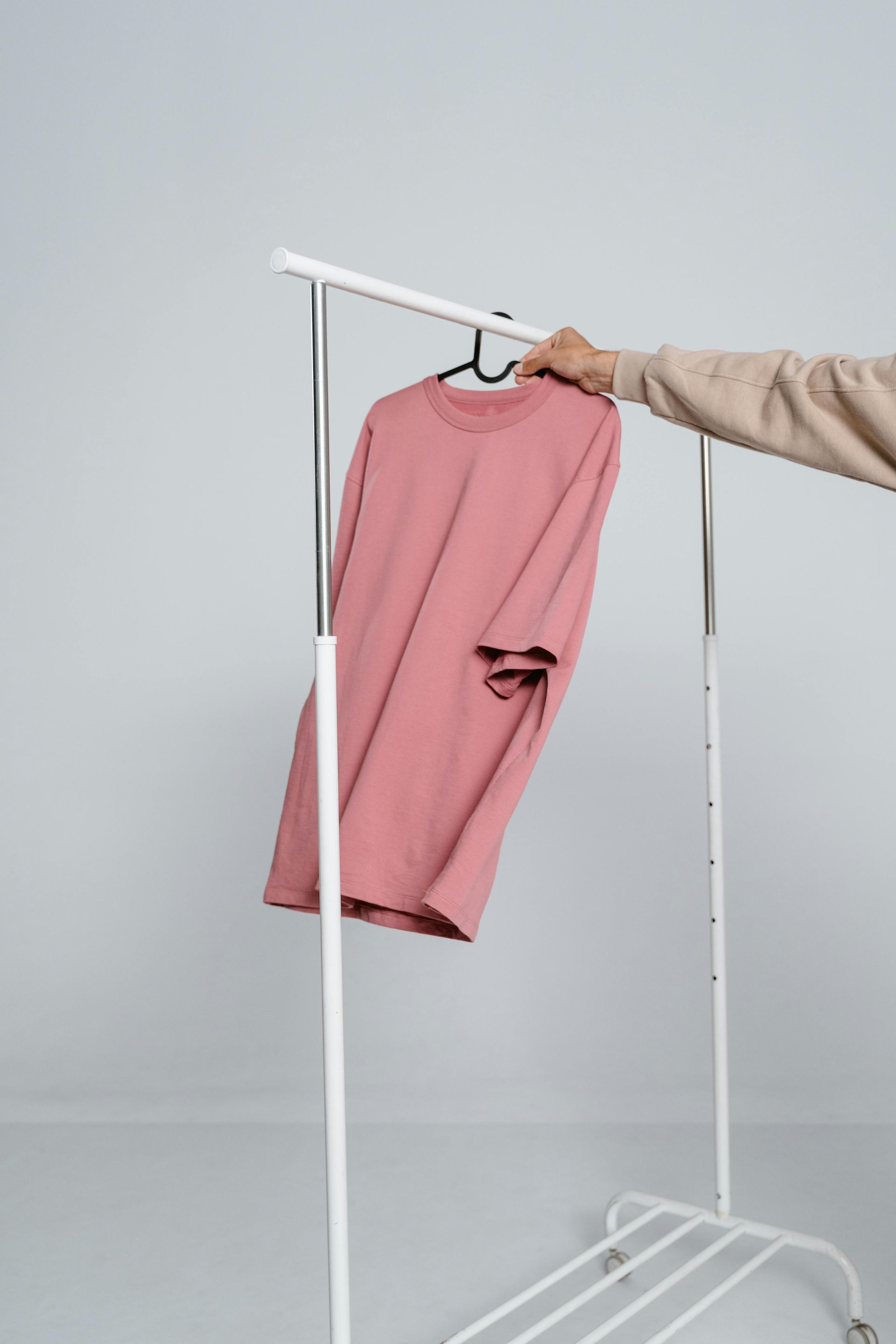 A single pink shirt is hung up on a clothing rack. 