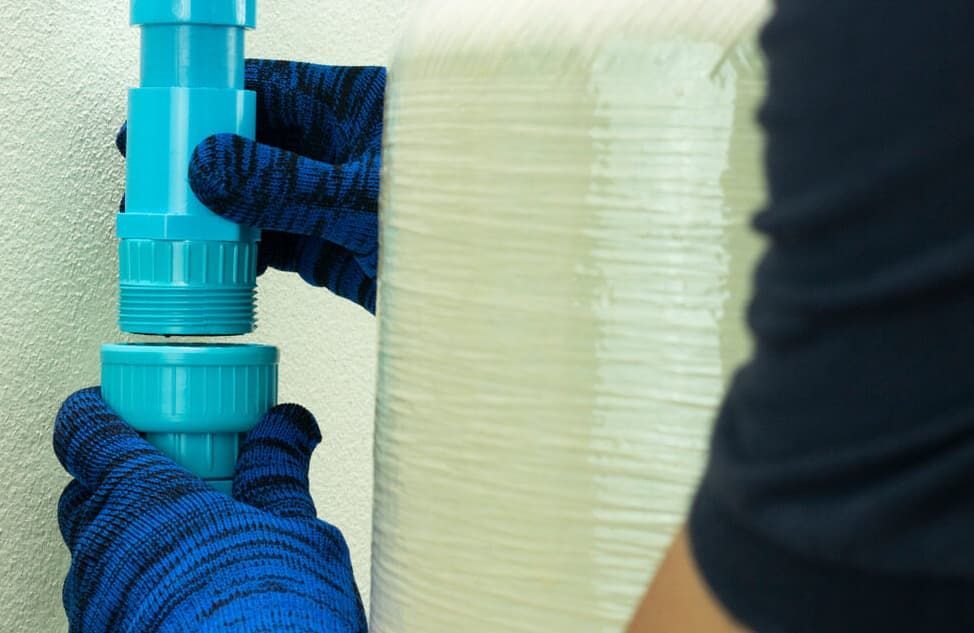 A Person Is Holding A Blue Pipe In Their Hands — JSB Plumbing & Gas In South Grafton, NSW