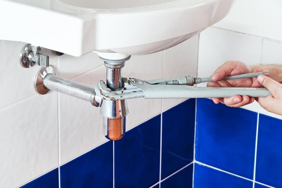A Person Is Fixing A Sink With A Wrench — JSB Plumbing & Gas In South Grafton, NSW