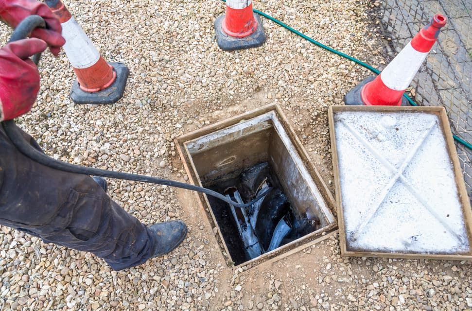 A Man Is Cleaning A Drain With A Hose — JSB Plumbing & Gas In South Grafton, NSW