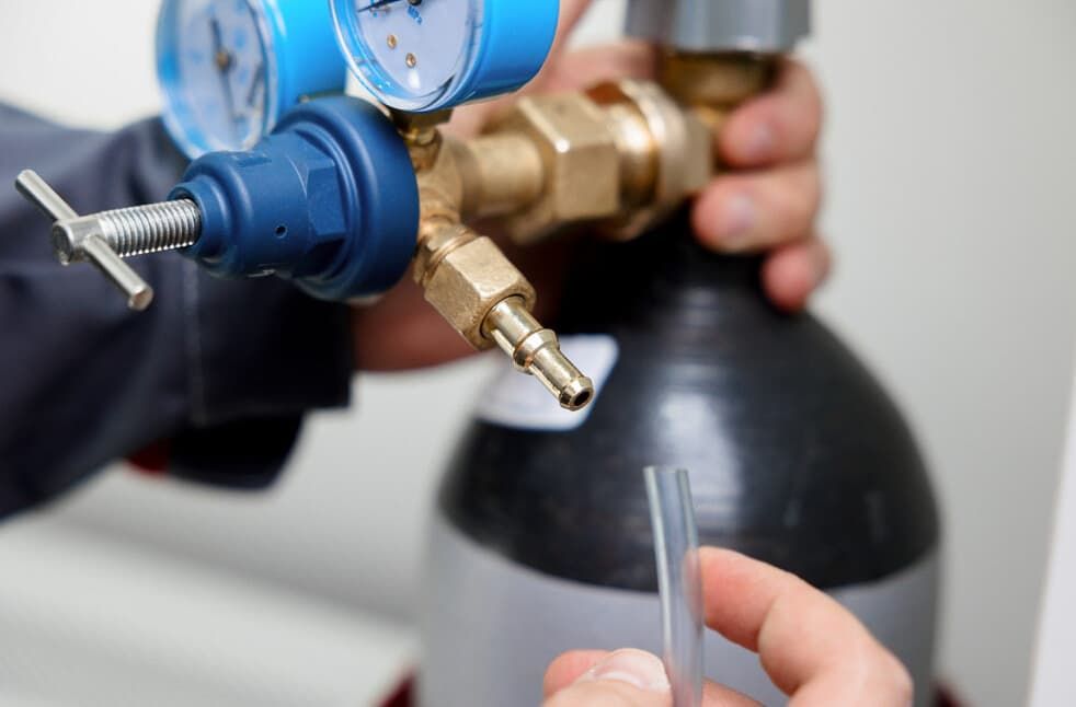 A Person Is Holding A Hose Next To A Gas Cylinder — JSB Plumbing & Gas In South Grafton, NSW