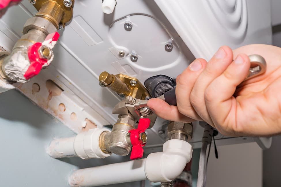A Person Is Fixing A Water Heater With A Wrench — JSB Plumbing & Gas In South Grafton, NSW