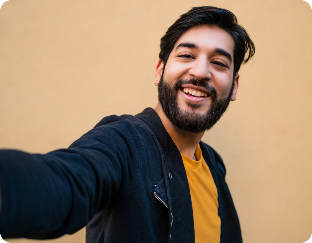 man with a beard smiling and taking a selfie