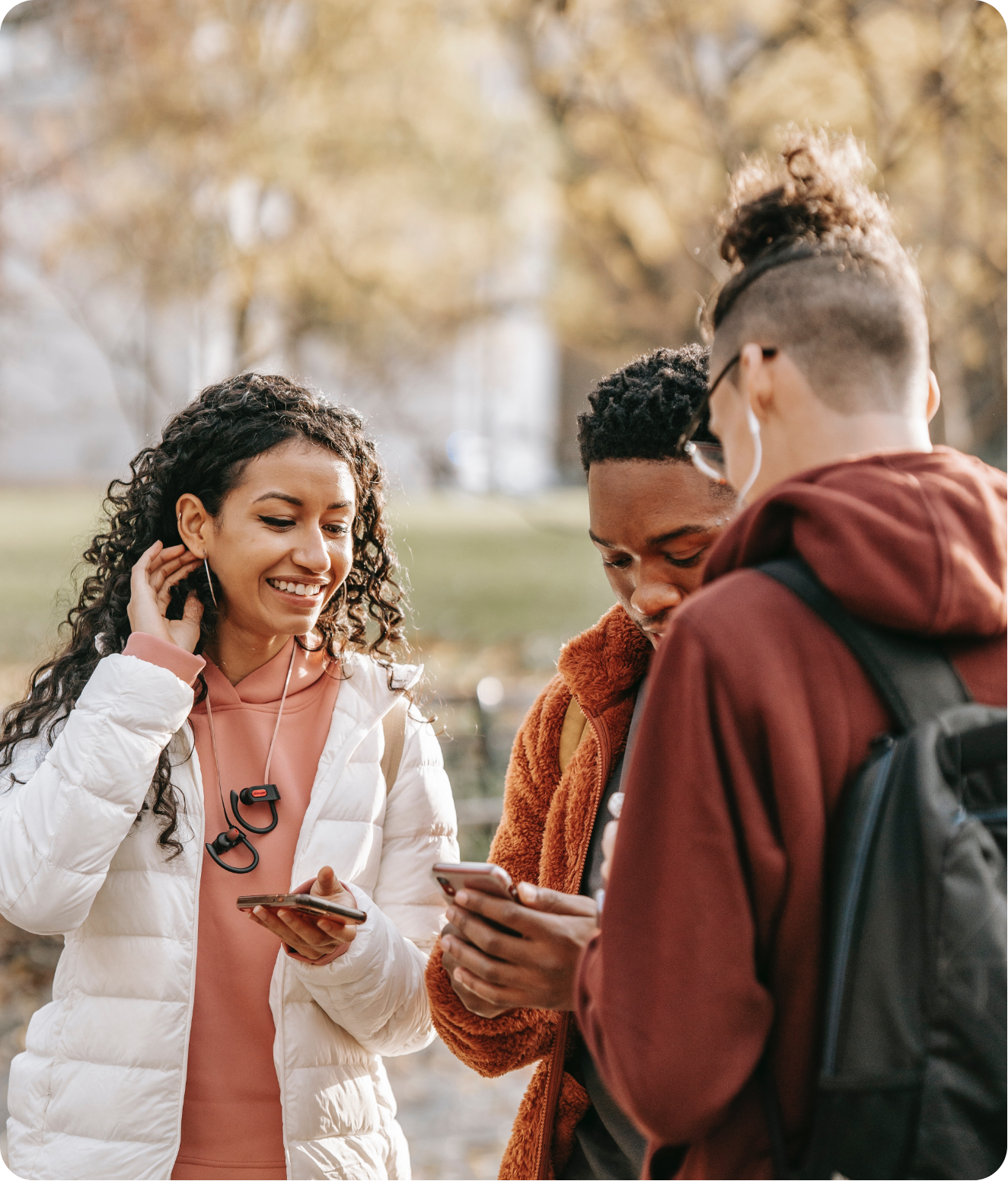 3 young people smiling and looking at their phones