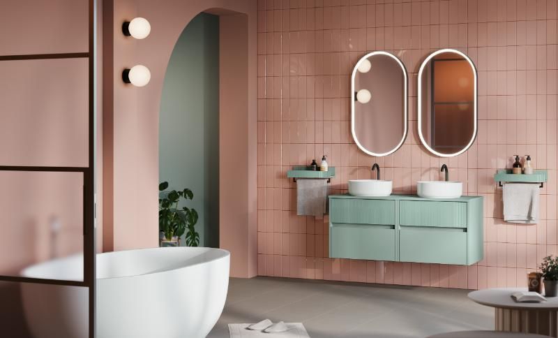 Un bagno con piastrelle rosa, due lavandini, una vasca e due specchi.