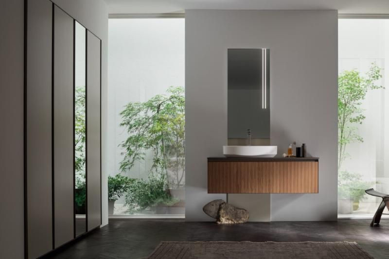 Un bagno con lavandino, specchio e armadietti