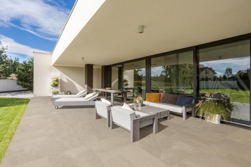 Una casa moderna con un ampio patio con sedie e tavolo.