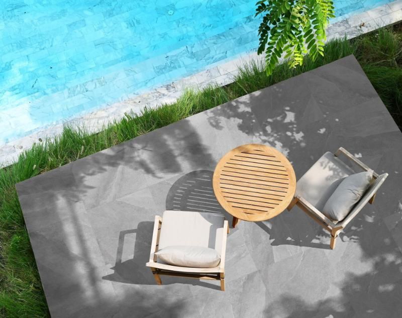 Un patio con tavolo e sedie accanto alla piscina.