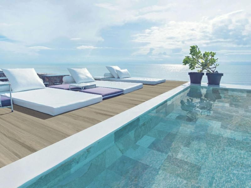 Una piscina con terrazza in legno con vista sull'oceano.