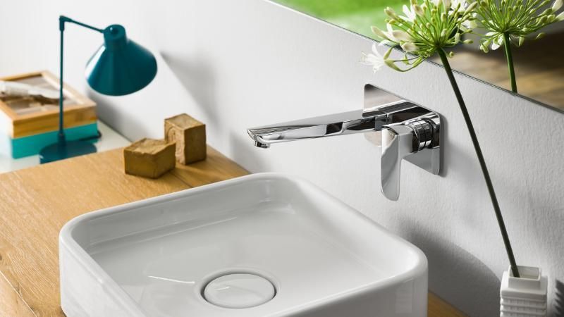 Un lavandino del bagno con rubinetto e una lampada su un bancone in legno.